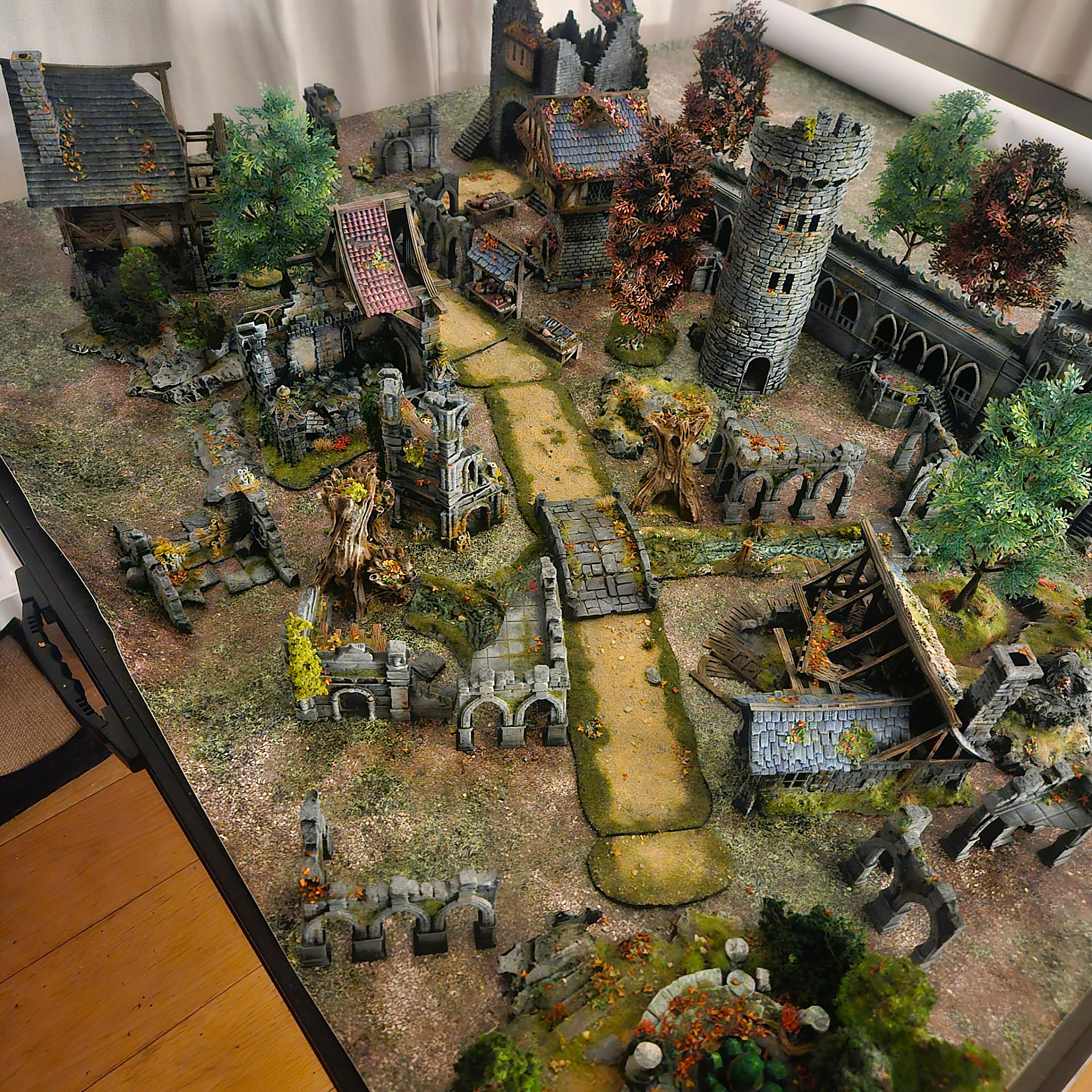 An overhead view of a detailed village with a stone tower and autumn trees