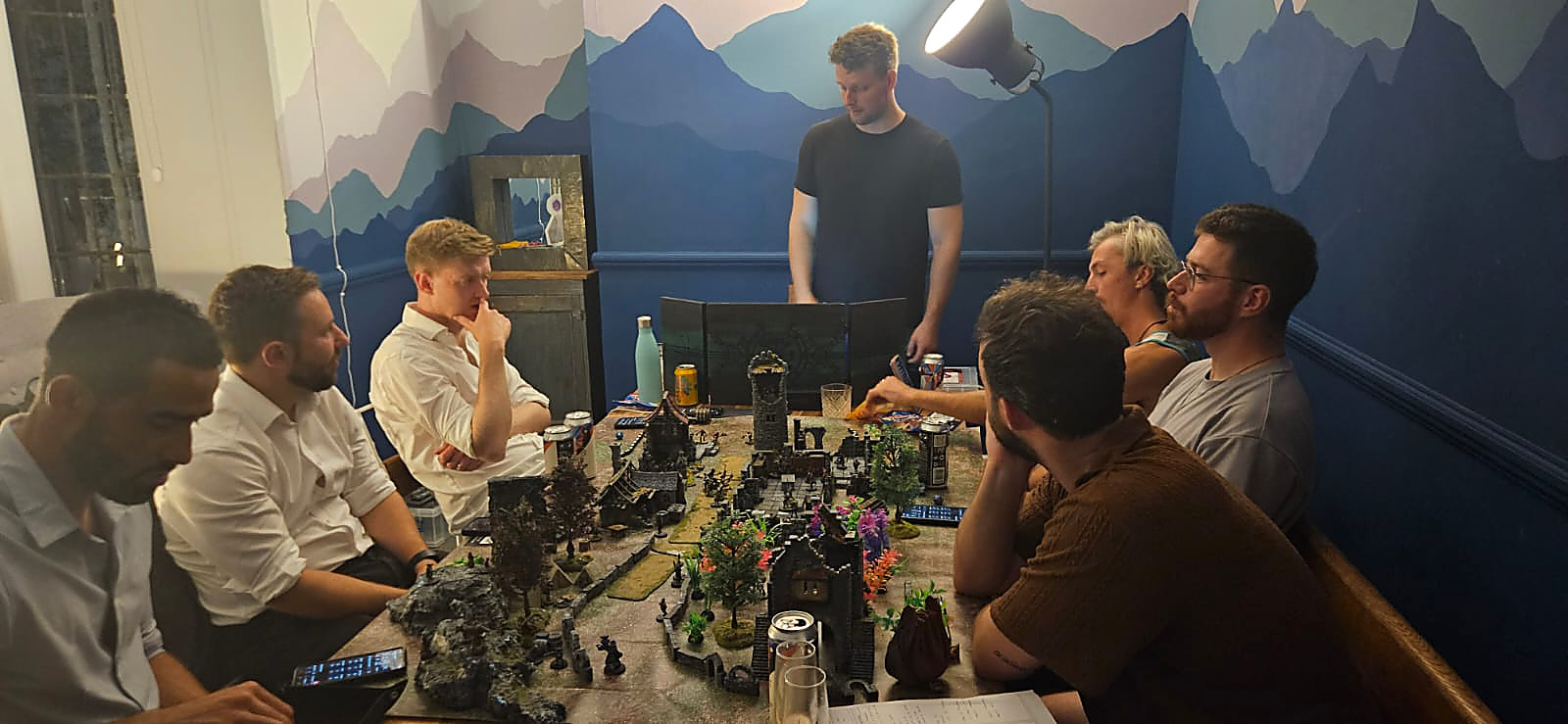A full party playing beneath a painted mountain mural
